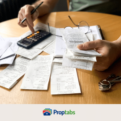 Close up of someone calculating rental property bills and receipts with a pen