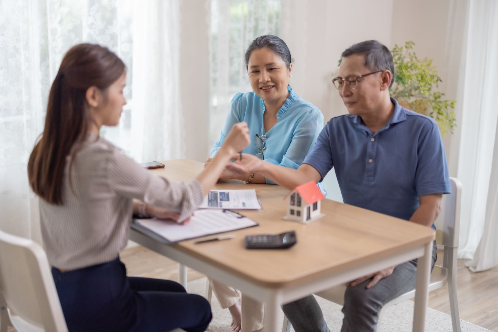 Couple sitting at the closing table signing real estate documents on the day they get the keys to their new home