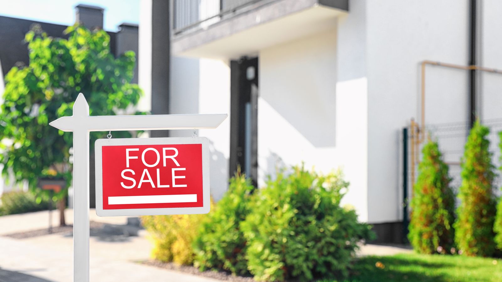 House with a for sale sign in the front yard during the touring stage of the home buying process